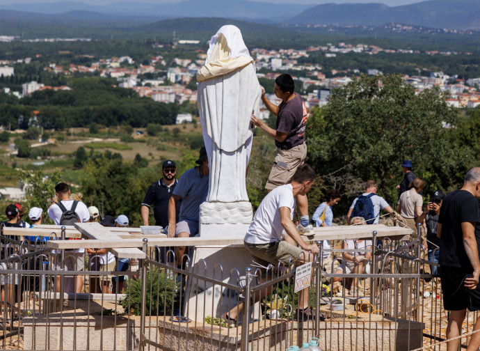 Volontari puliscono la statua vandalizzata della Madonna sul Podbrdo (Ap via LaPresse)(