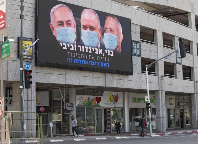 Tel Aviv, poster con Netanyahu, Lieberman e Gantz con mascherina